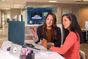 Two business women in front of a laptop going through updates.