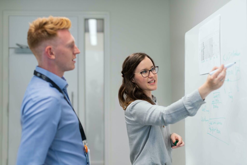 Business women presenting information on a whiteboard to business man